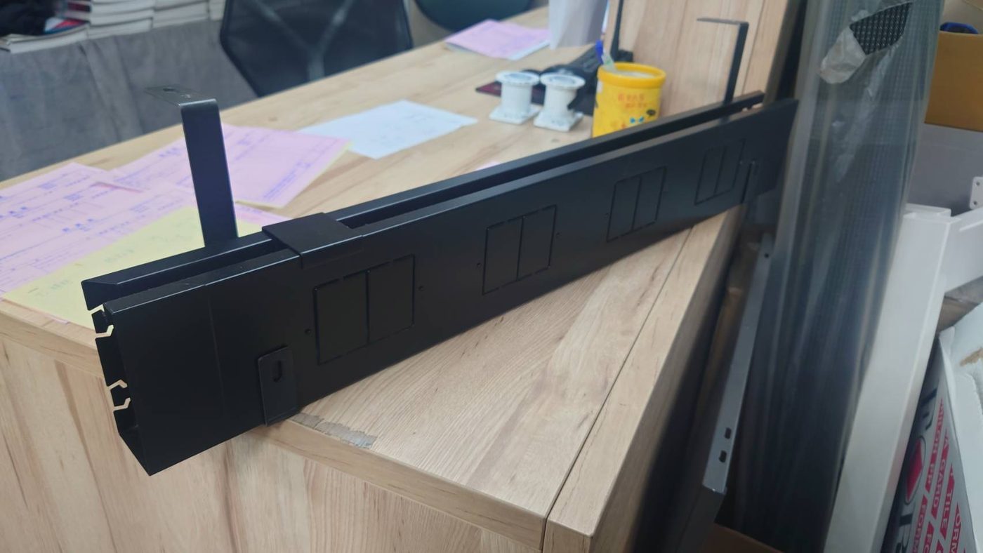 木紋桌板下一支黑色鋼製走線槽,有多個方形孔位