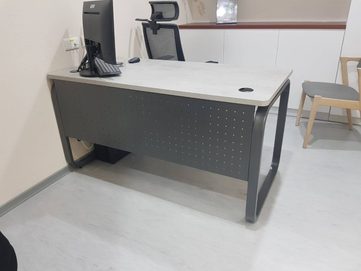 深灰色桌腳工作桌,正面下方深灰檔板上滿佈小圓洞
