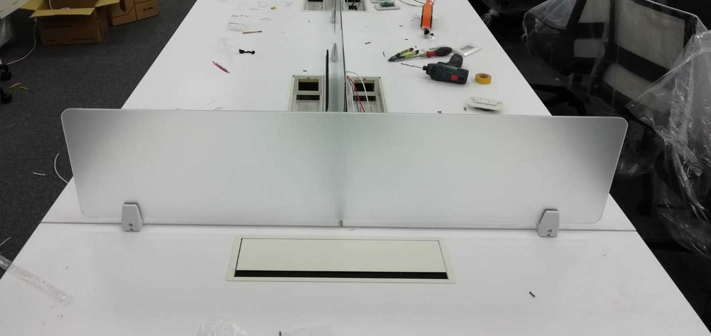 白色長桌中間立一片霧面玻璃桌屏,下方有兩顆銀色夾具,桌面有一組嵌入式線盒