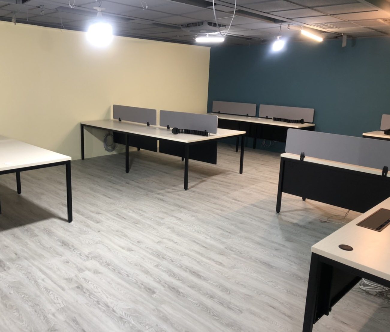 白色桌面黑色桌腳的工作站桌,桌面立灰色桌屏,對坐排列