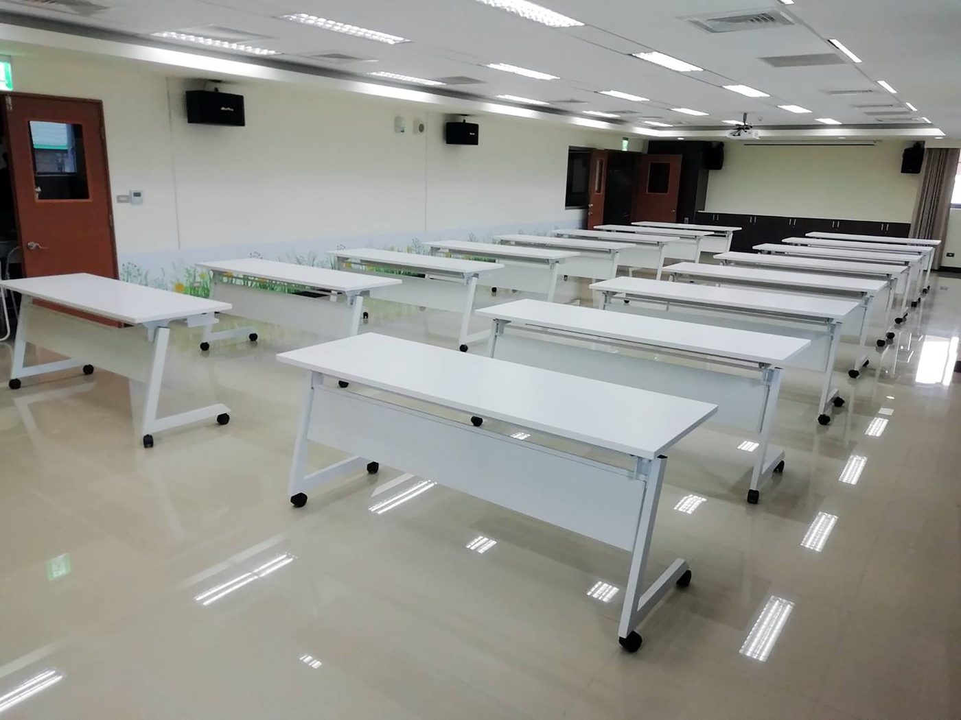 大教室裡多張白色掀合桌排成好幾排